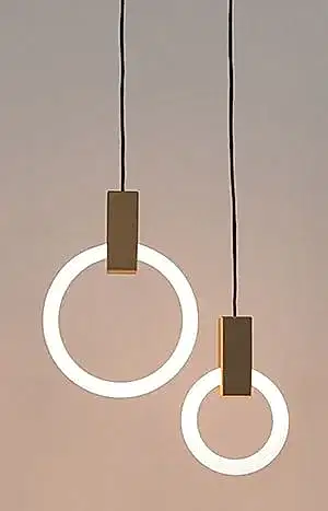 Nötr bir fon üzerinde siyah kordonlara asılı, beyaz ışıklı halkalara sahip iki dairesel sarkıt lamba, iç mimar tasarımının zarafetini yansıtıyor.