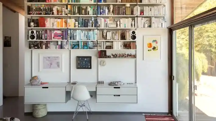 İçinde birçok kitaplık ve altın kurala göre tasarlanmış bir çalışma masası bulunan bir oda.