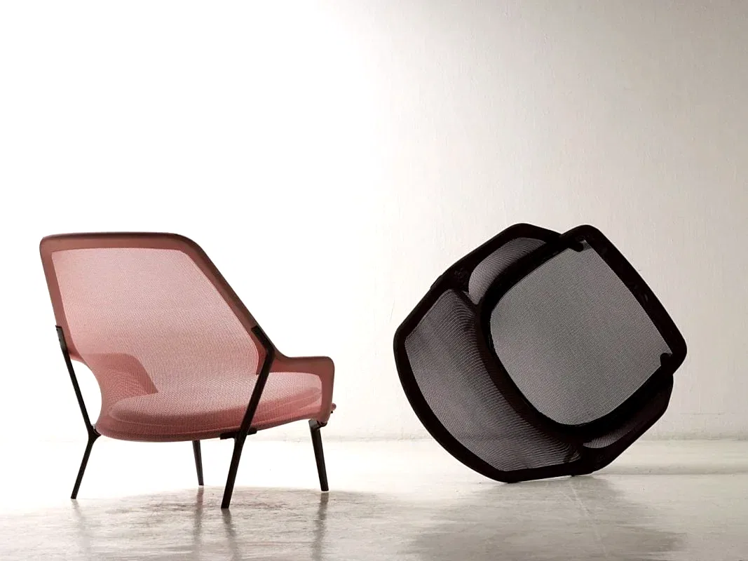 Pembe fileli koltuk, beyaz zemin üzerinde siyah fileli geometrik bir objenin yanında durarak modern iç mimar tasarımın özünü yansıtıyor.