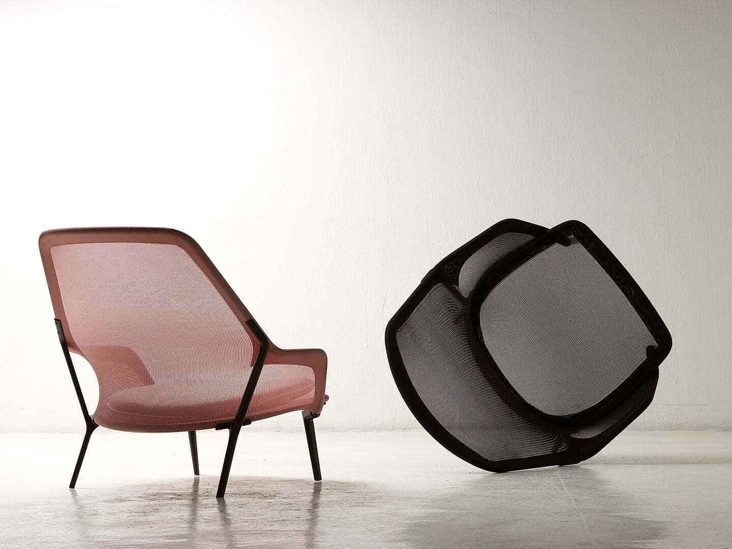 Pembe fileli koltuk, beyaz zemin üzerinde siyah fileli geometrik bir objenin yanında durarak modern iç mimar tasarımın özünü yansıtıyor.