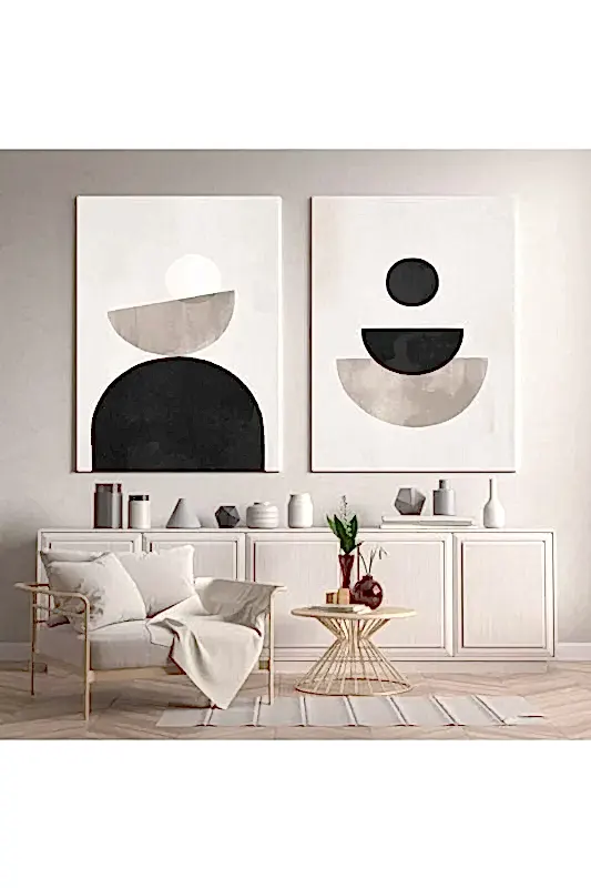 İç mimarın zarafetle buluştuğu bu modern oturma odasına adım atın. Soyut sanat eserleriyle süslenmiş, rahat bir örtüyle örtülü beyaz bir sandalye ve dekoratif eşyalara sahip açık renkli ahşap bir büfe, davetkar bir ambiyans sunuyor. Vazolu yuvarlak bir sehpa bu tasarım şaheserini tamamlıyor.