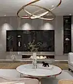 "Premium" koleksiyonunda dairesel avize, mermer yuvarlak masa, iç mimar tarafından küratörlüğü yapılan dekoratif vazolar ve şömineli minimalist bir taş duvar bulunan modern bir oturma odası yer alıyor. Kitaplarla dolu raflar ve dekor, villa veya çevrimiçi tasarım ilhamı için görünümü tamamlıyor.