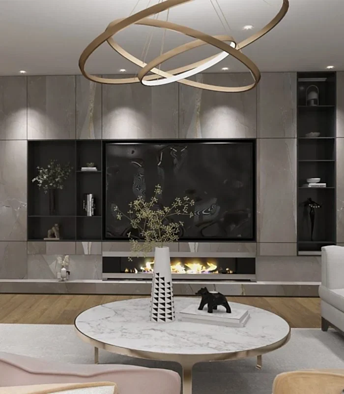 "Premium" koleksiyonunda dairesel avize, mermer yuvarlak masa, iç mimar tarafından küratörlüğü yapılan dekoratif vazolar ve şömineli minimalist bir taş duvar bulunan modern bir oturma odası yer alıyor. Kitaplarla dolu raflar ve dekor, villa veya çevrimiçi tasarım ilhamı için görünümü tamamlıyor.