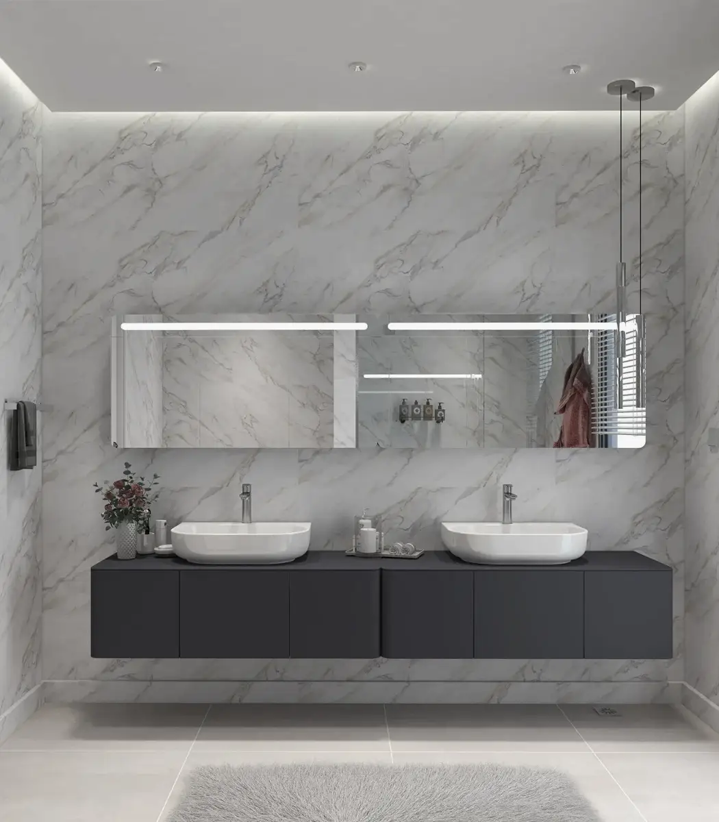 BANYO TASARIMI, mermer duvarlar, çift lavabo, büyük aynalar ve gri yüzen bir dolapla modern bir banyo sergiliyor. Ünlü bir iç mimar tarafından tasarlanan villa tarzı mekan, dolabın önündeki halıya sıcak bir ışık veren yumuşak bir aydınlatmaya sahip.